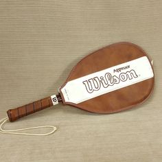 a brown and white leather paddle with the word awesome on it's side sitting on a tan surface