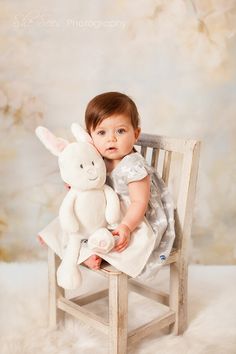 a baby sitting in a chair holding a stuffed animal