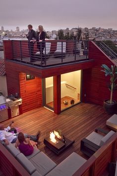 two people are sitting on the roof of a house with a fire pit in the middle