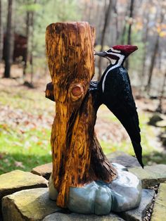 a statue of a bird on top of a piece of wood in the woods next to a tree stump