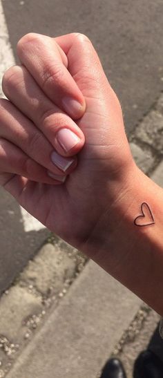 a woman's arm with a small heart tattoo on the left side of her wrist