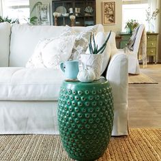 a large green vase sitting on top of a rug in front of a white couch