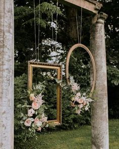 an old photo frame with flowers hanging from it's sides in front of a tree