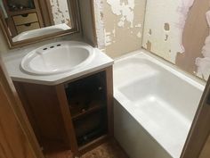 a bathroom with a sink, mirror and bathtub in it's corner next to a wall that has been torn off