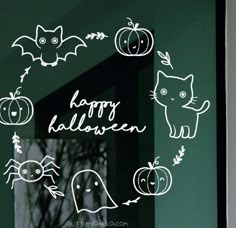 a window with halloween stickers on it in front of a green wall and black door