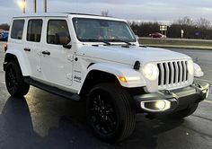 a white jeep parked in a parking lot next to some lights and cars on the street