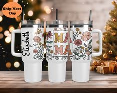 three personalized travel mugs on a table next to a christmas tree and presents