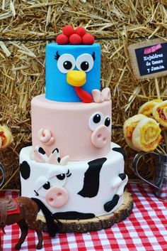 a three tiered cake with farm animals on it and straw bales in the background