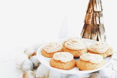 a white plate topped with frosted cupcakes next to christmas decorations