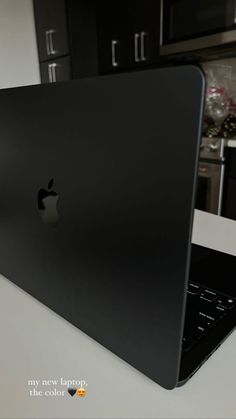 an apple laptop computer sitting on top of a white counter next to a black oven