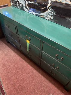 a large green dresser sitting on top of a carpeted floor next to a wall