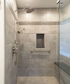 a walk in shower sitting next to a window and tiled floored wall with glass doors