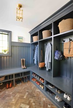 an organized mud room with blue walls and wooden flooring, built in cubbys