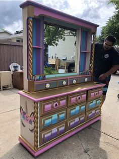 a man standing in front of a colorful dresser with mirrors on it's sides