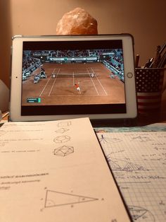 a tablet computer sitting on top of a desk next to papers and pencils,