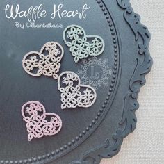 three heart shaped brooches sitting on top of a black plate with the words waffle heart