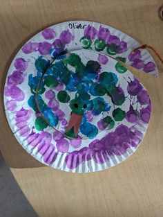 a paper plate with purple and blue flowers on it sitting on top of a wooden table