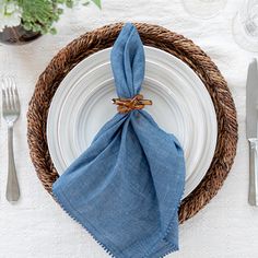 a place setting with blue napkins and silverware on a white table cloth covered plate