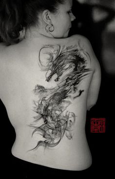 the back of a woman's body is covered in black and white ink as she shows off her tattoo design