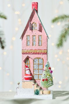 a pink doll house sitting on top of a table next to a small christmas tree