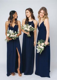 three bridesmaids in navy blue dresses holding bouquets