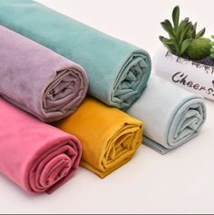 four different colored towels sitting next to each other on a white surface with succulents in the background