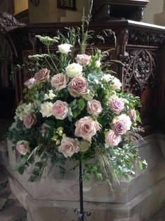 a bunch of flowers that are in a vase on a stand with some leaves around it