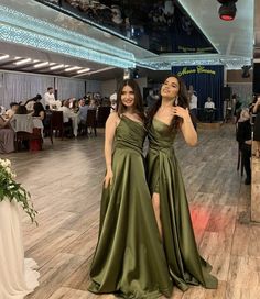 two women standing next to each other in front of a crowd at a formal event