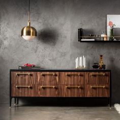 a black and gold sideboard with two hanging lights above it, next to a gray wall