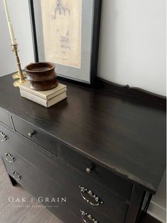 an old dresser with a wooden bowl on top and a candle sitting on top of it