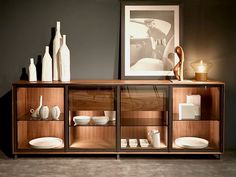 a wooden cabinet with glass doors and shelves filled with vases, plates and other items