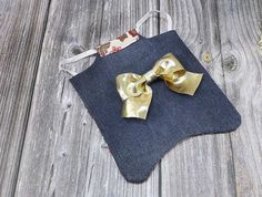 a small blue bag with a gold bow on the front sitting on a wooden surface