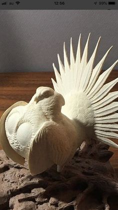 a sculpture of a bird with its wings spread out on a wooden table next to rocks