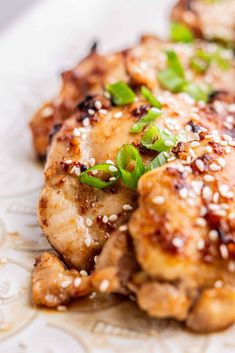 chicken with sesame seeds and green onions on a plate