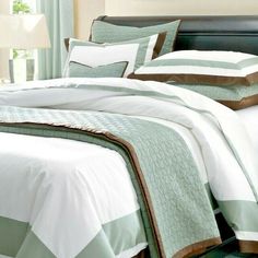 a bed with green and white comforters in a bedroom