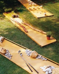 two wooden boards with tools on them laying in the grass next to rocks and plants