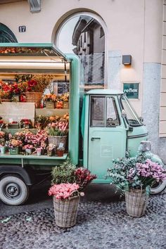 a green truck parked next to a building filled with flowers