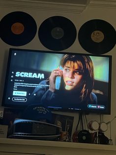 a flat screen tv mounted to the side of a wall next to record discs on a shelf