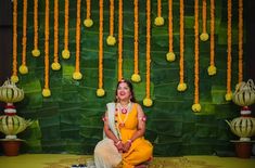 a woman is sitting on the floor in front of some flowers and hanging garlands