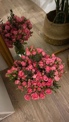 pink roses are sitting on the table in front of a mirror and potted plant