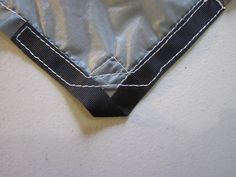 the corner of a piece of cloth with white stitching on it and a black ribbon at the bottom