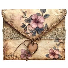 an old envelope decorated with pink flowers and a heart tied to the front, on a white background