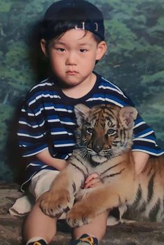 a young boy is holding a tiger cub