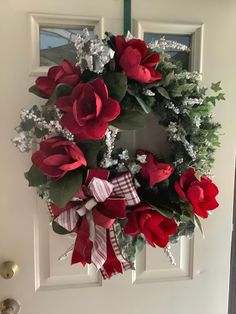 a wreath with red roses and greenery on the front door