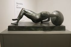 a sculpture of a woman laying on top of a metal object in a museum display