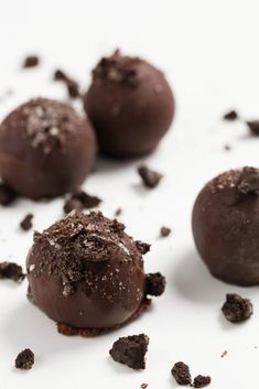 three chocolate truffles are on a white surface with crumbs around them