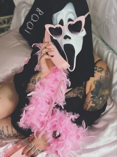 a woman wearing a mask and pink feathers on her stomach while talking on a cell phone