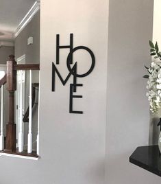 there is a sign that says home on the wall next to a vase with flowers