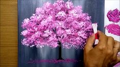 someone is painting a pink tree with crayons on the paper and it looks like they're doing something right now