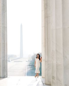 a woman in a white dress standing next to the washington monument